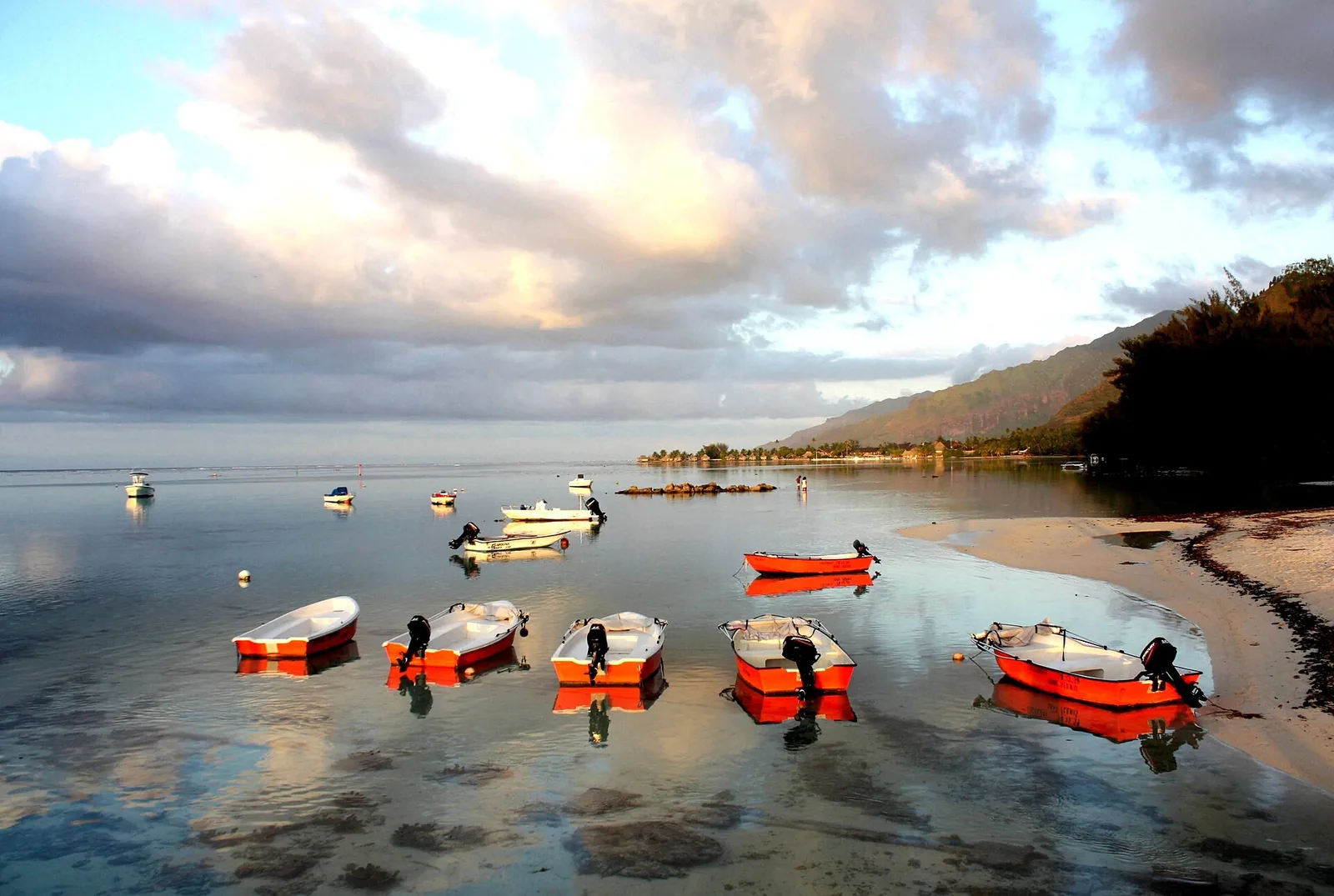 Barques rouges au mouillage sur la plage de Tiahura, côte nord-ouest de Moorea, au crépuscule