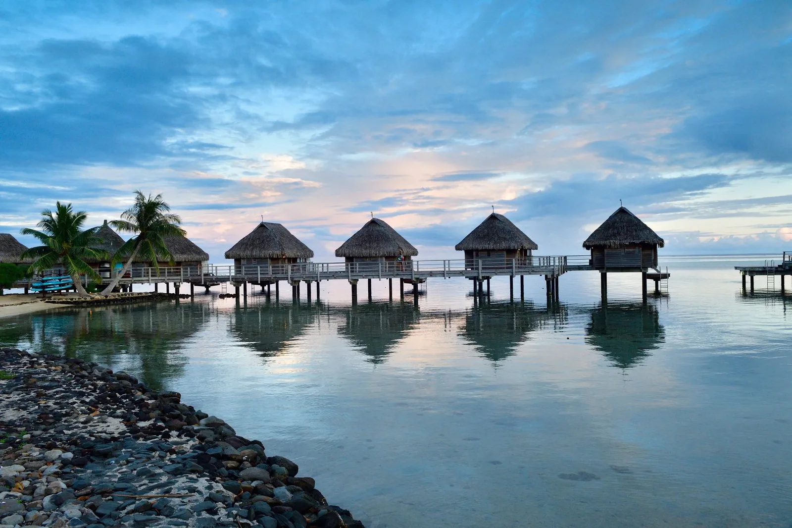 Bungalows sur pilotis et ponton au crépuscule dans le lagon de Moorea, Polynésie française