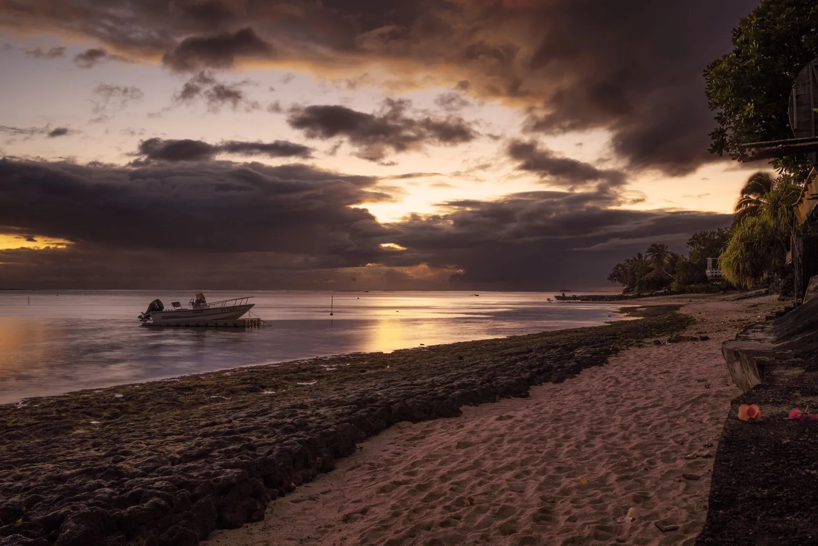 Coucher de soleil sur une plage de Moorea avec un bateau amarré dans le lagon