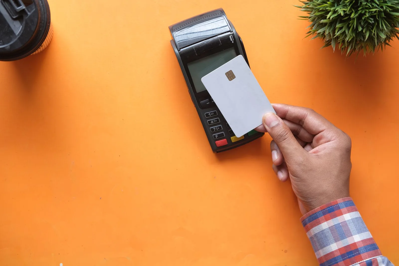 Main tendant une carte bancaire vers un terminal de paiement