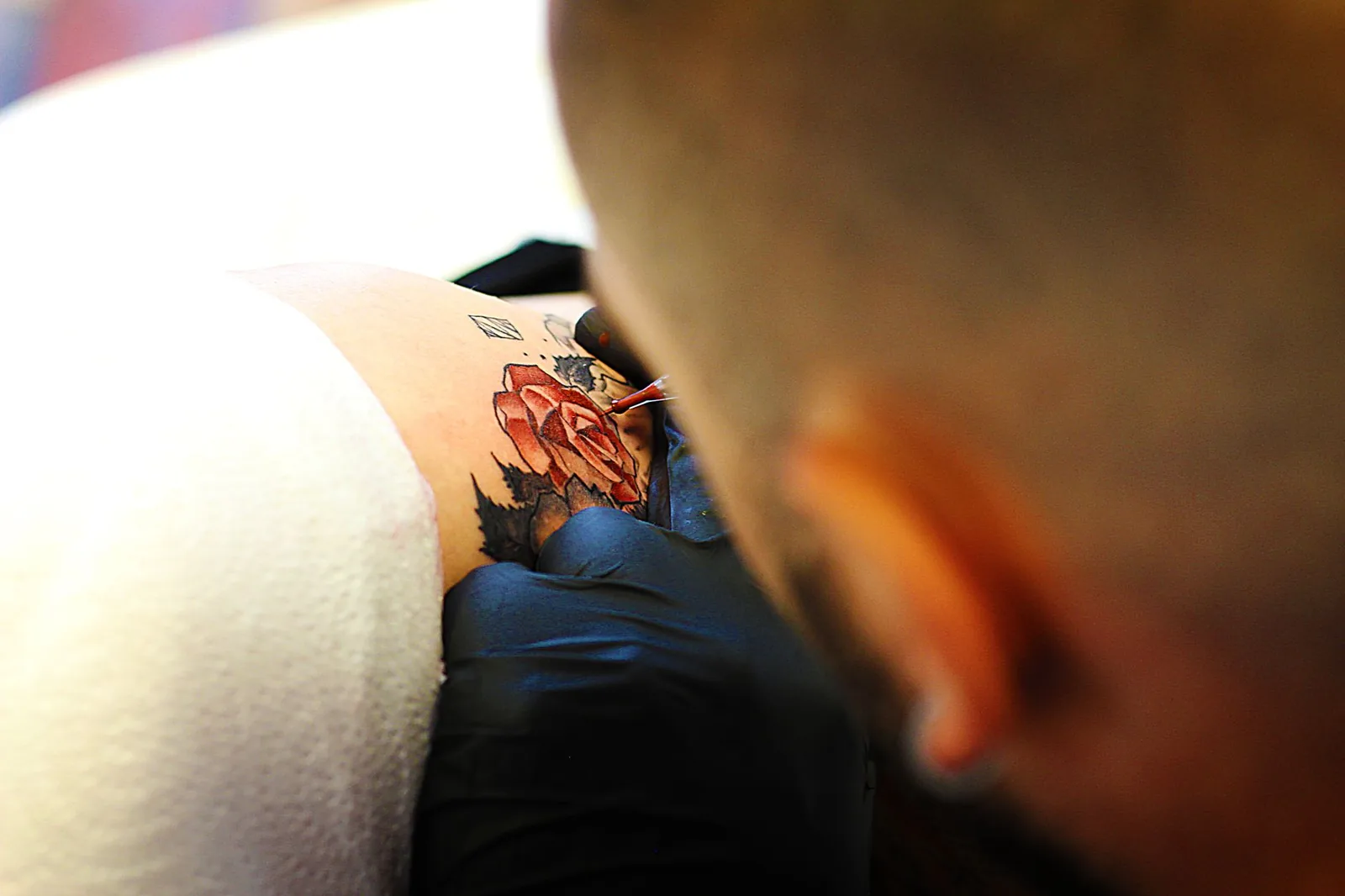Tatoueur ganté au travail en studio, matériel stérile et geste précis